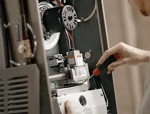 Furnace repair technician inspecting internal components and wiring in Portland, OR