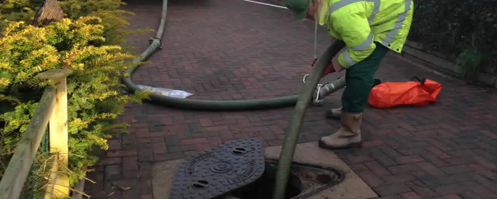 Septic tank cleaning technician servicing a septic tank with a vacuum hose in Portland, OR