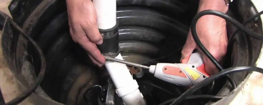 Sump pump installation technician connecting PVC discharge piping in Portland, OR